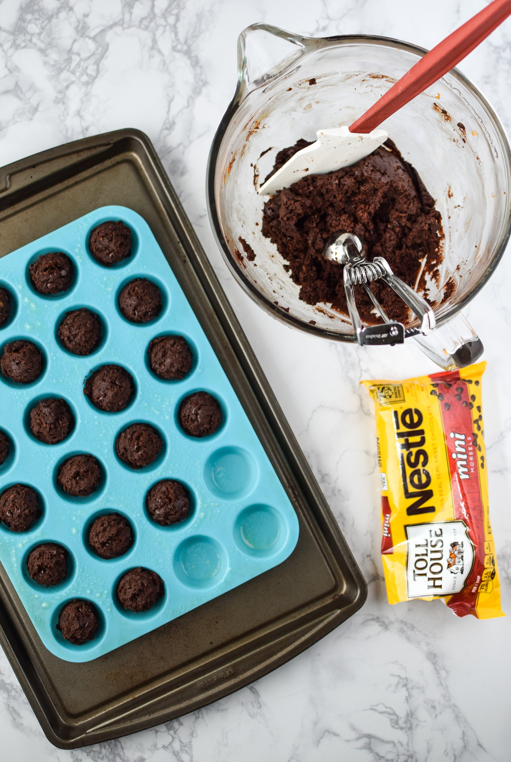 Freezer Friendly Sweet Potato Brownie Bites being made - using a scoop to place into a silicone mini muffin tin.