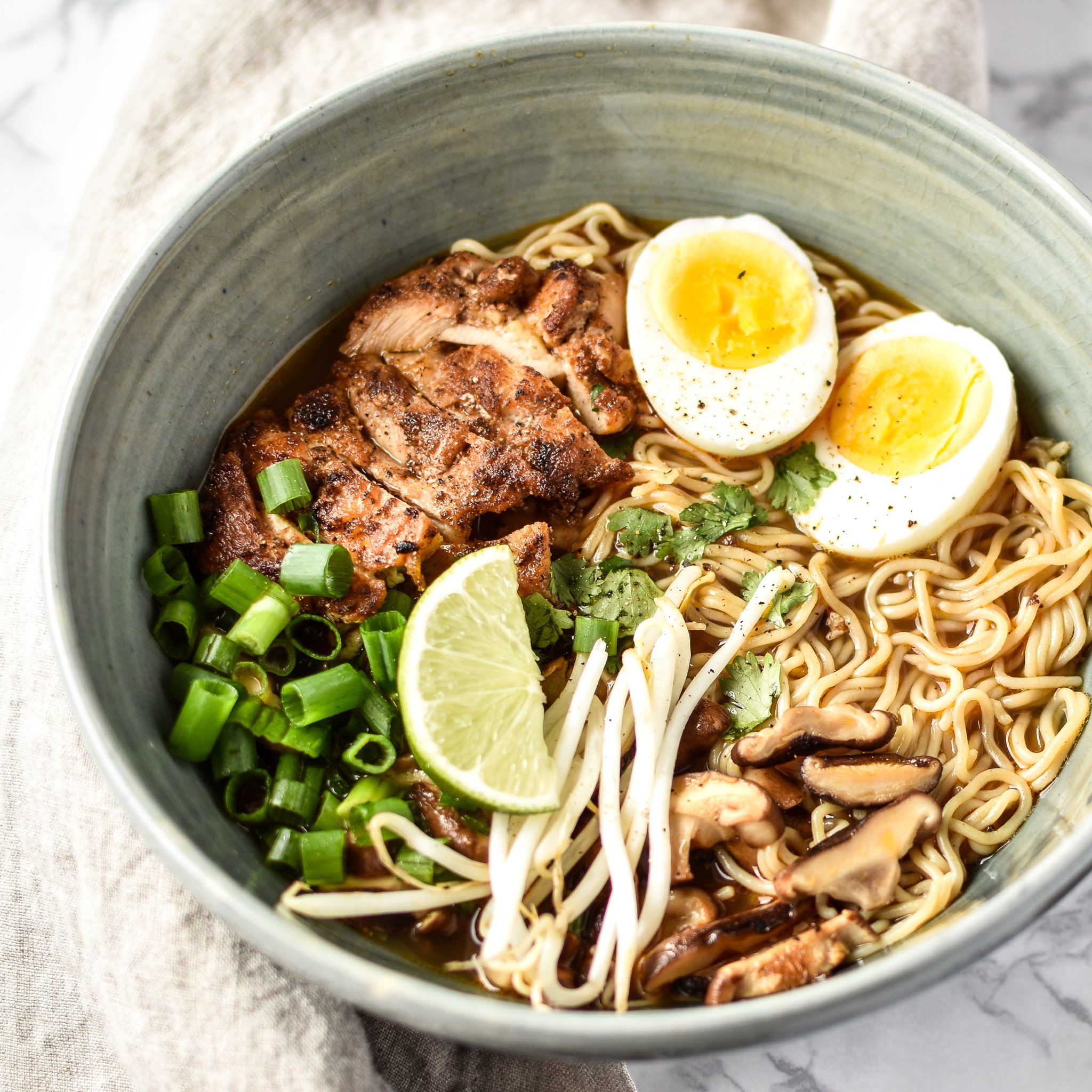bowl of Simple Shiitake Mushroom Chicken Ramen recipe topped with onions sprouts and an egg