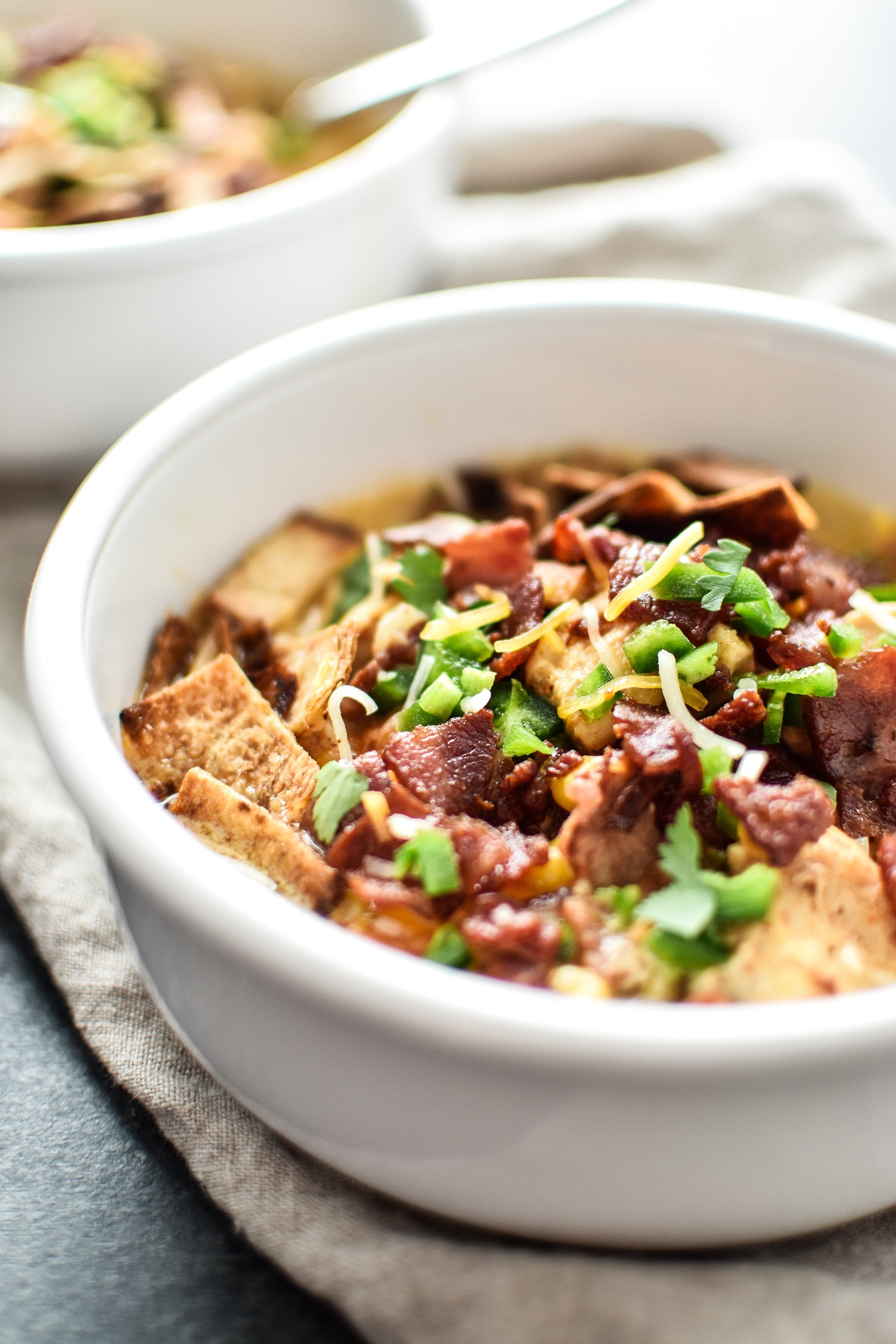 A bowl of jalapeno popper chicken soup from the side with toppings.