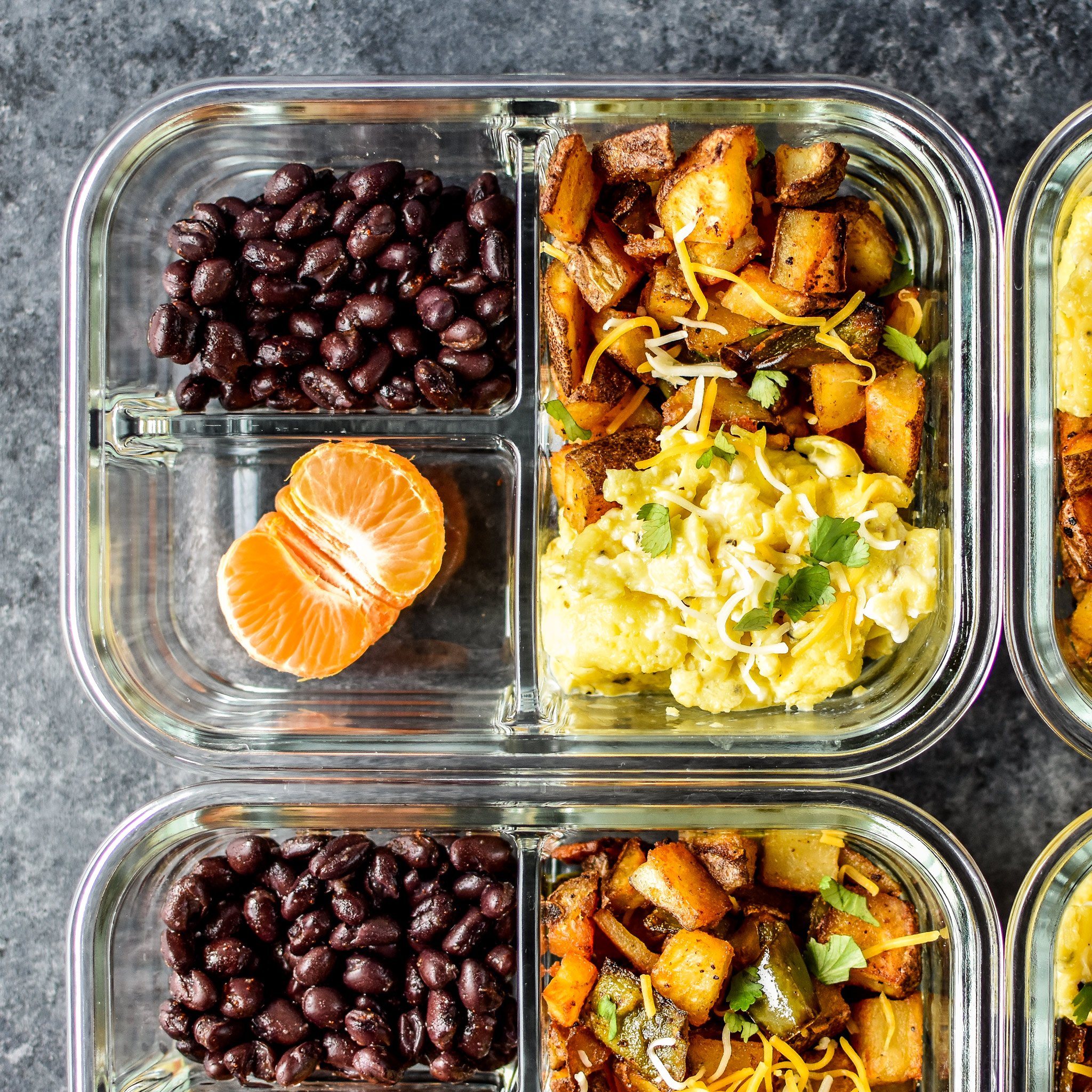 A close up on the Southwest Roasted Potato Breakfast Meal Prep bowl, top view. Potatoes, beans, eggs, half a citrus.