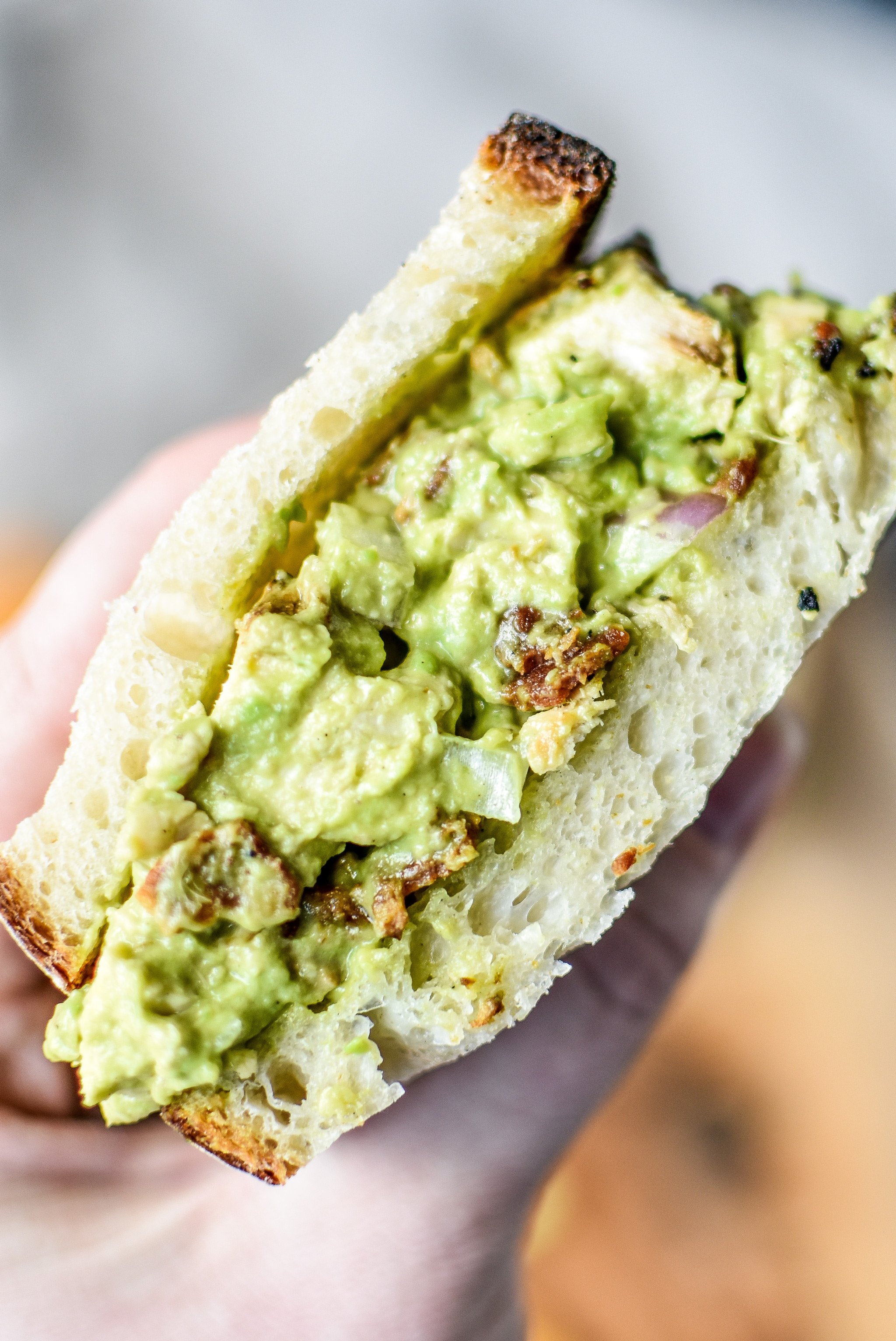 Holding a half of the delicious chicken bacon avocado salad sandwich.