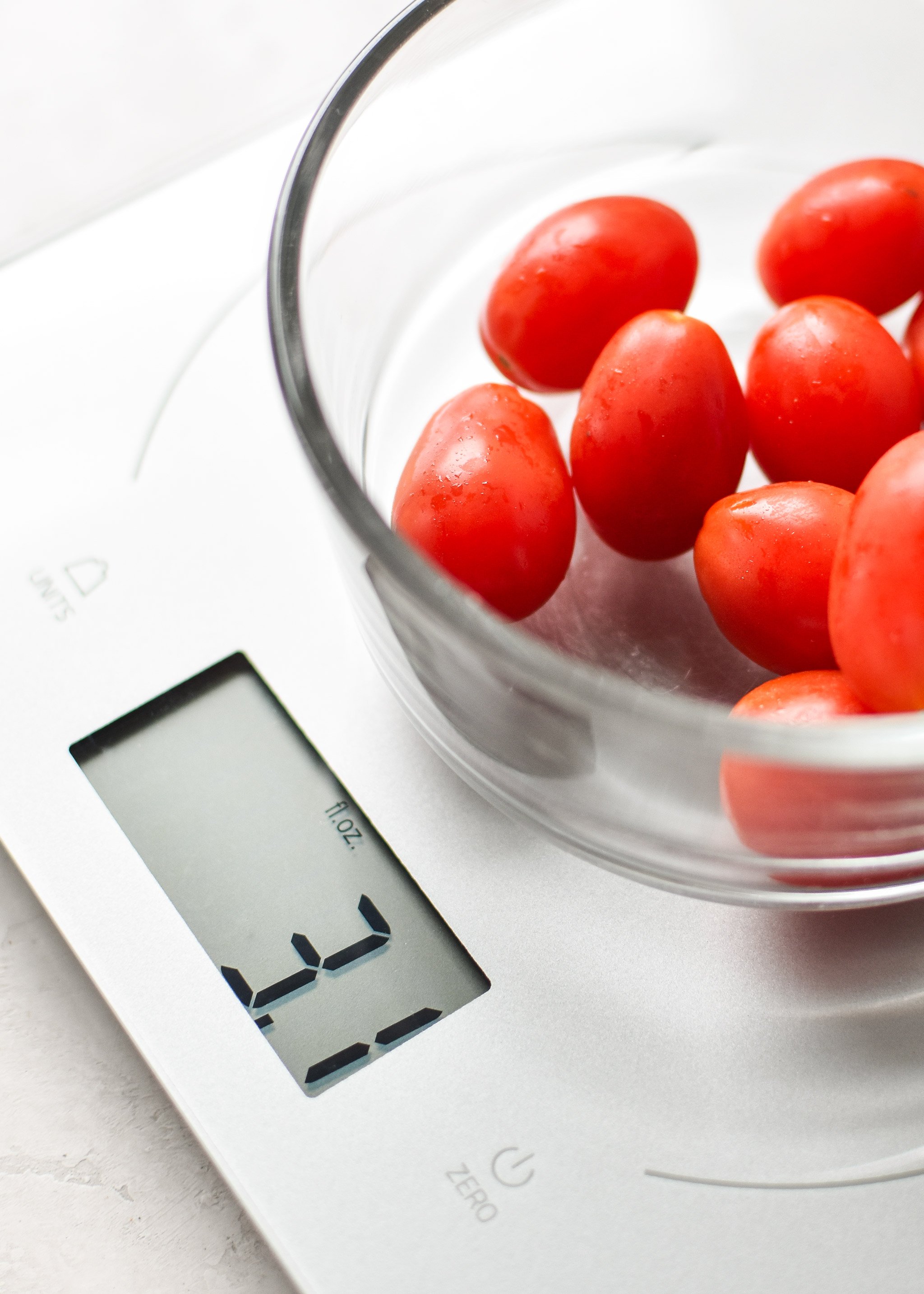 Portioning grape tomatoes for meal prep using a kitchen scale.