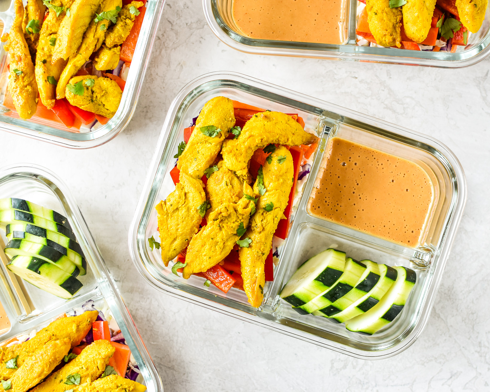 Meal Prep Satay Inspired Thai Chicken Salad Bowls in glass meal prep containers with spicy peanut sauce.