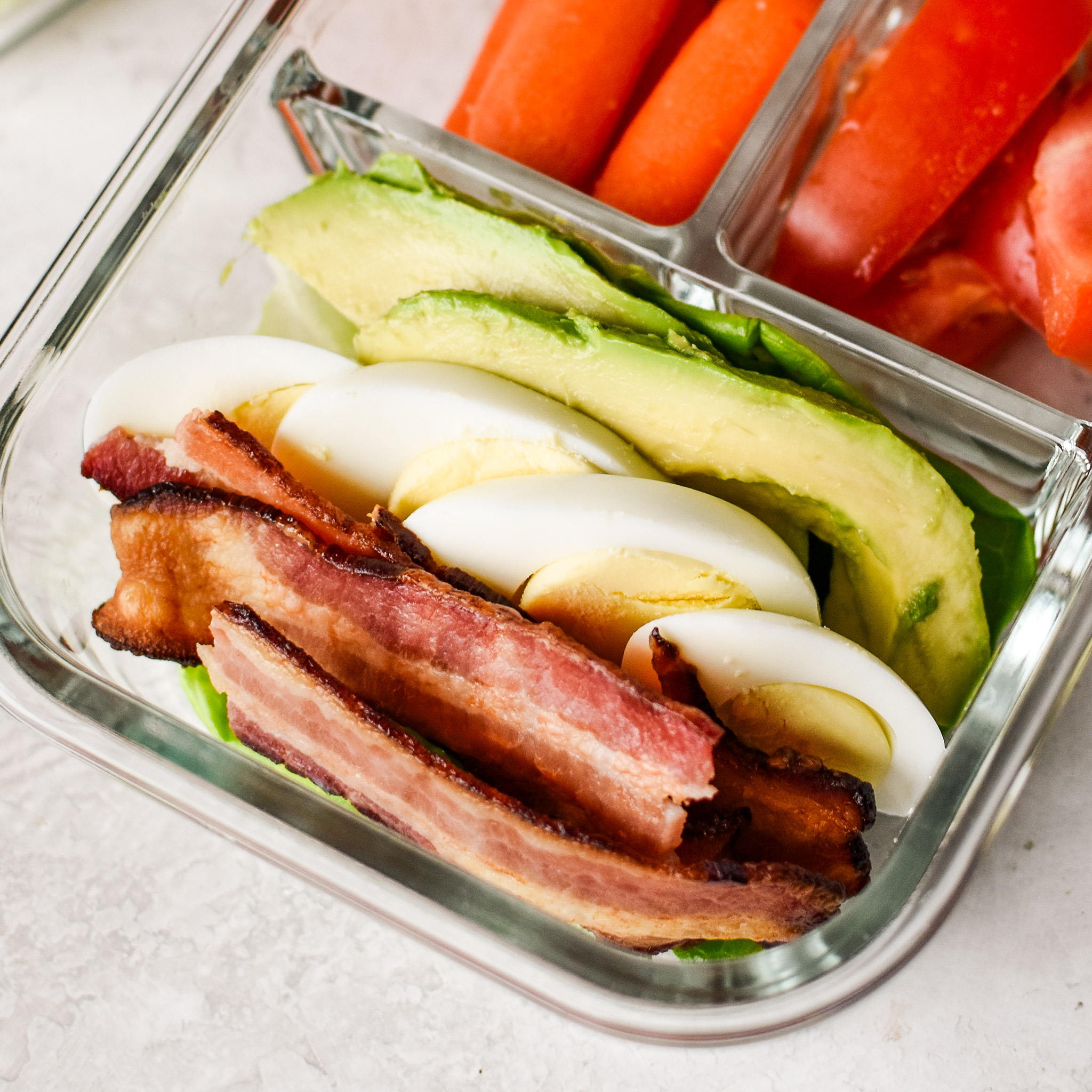 Close up of the BLTA lettuce wraps meal prep with bacon, tomato, avocado, and hard boiled eggs.