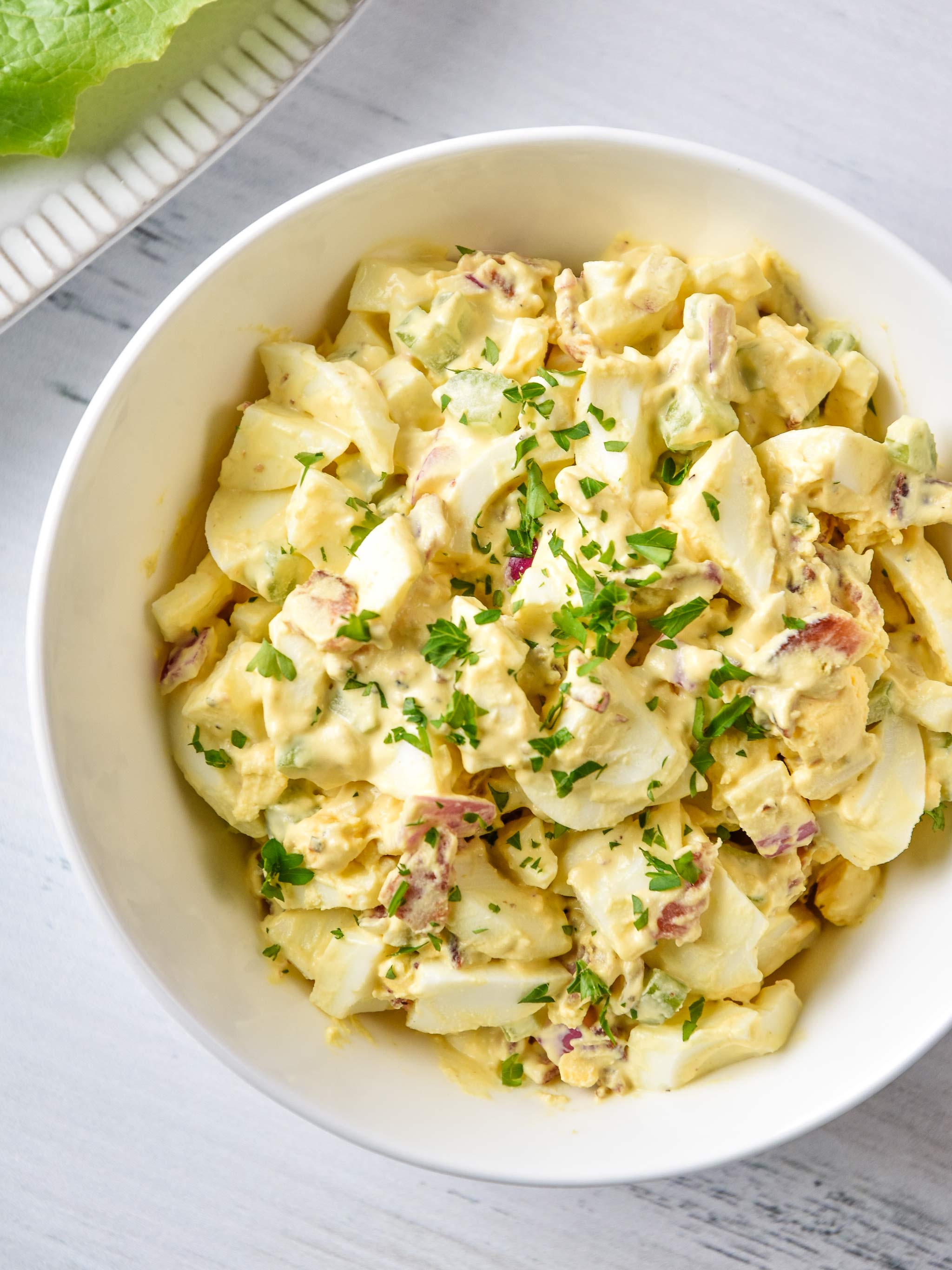 whole30 egg salad with bacon pictured from above in a bowl with parsley sprinkled on top