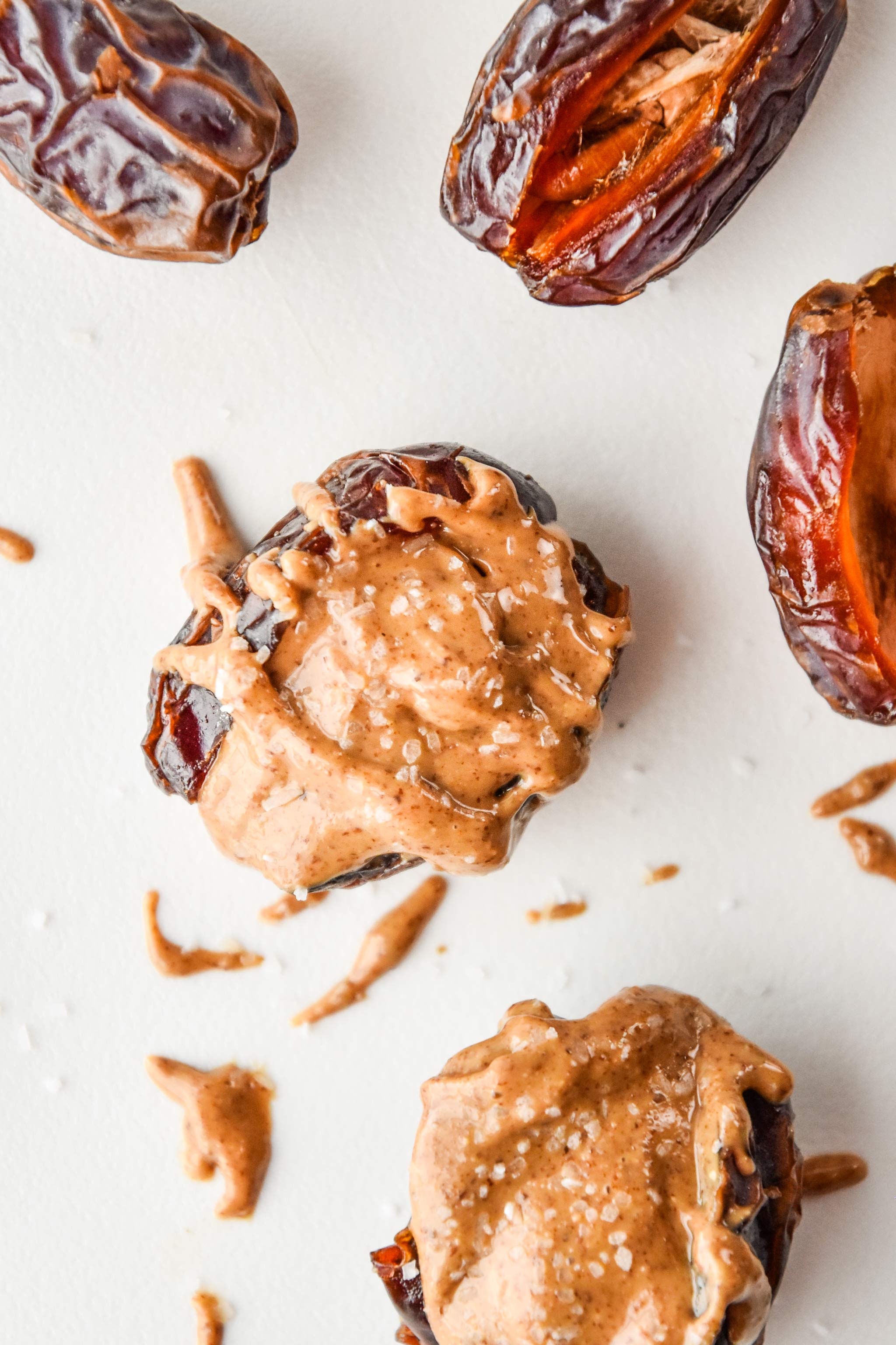 Salted almond butter stuffed dates drizzled with almond butter on a cutting board