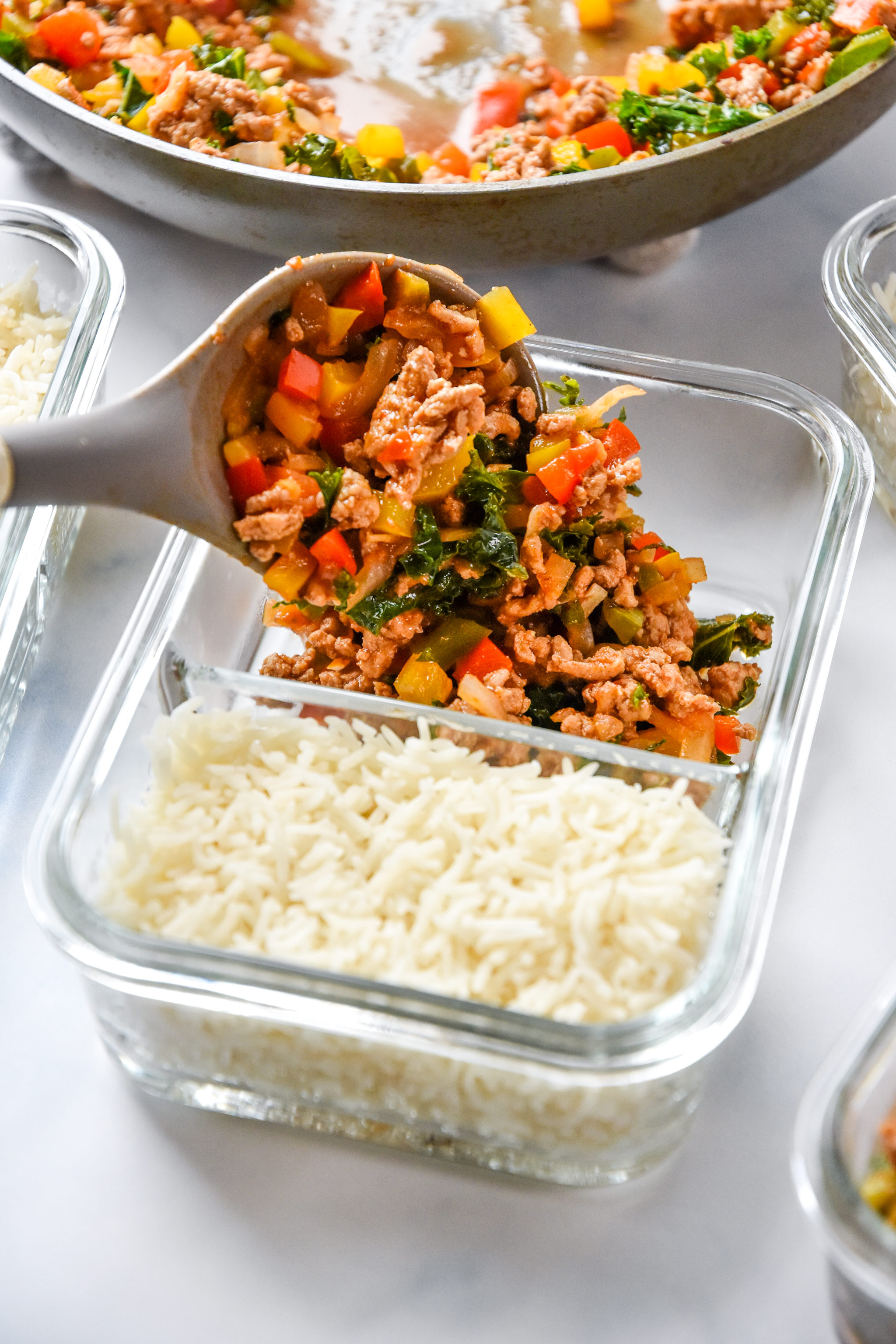 scooping chipotle ground turkey skillet mixture into meal prep container