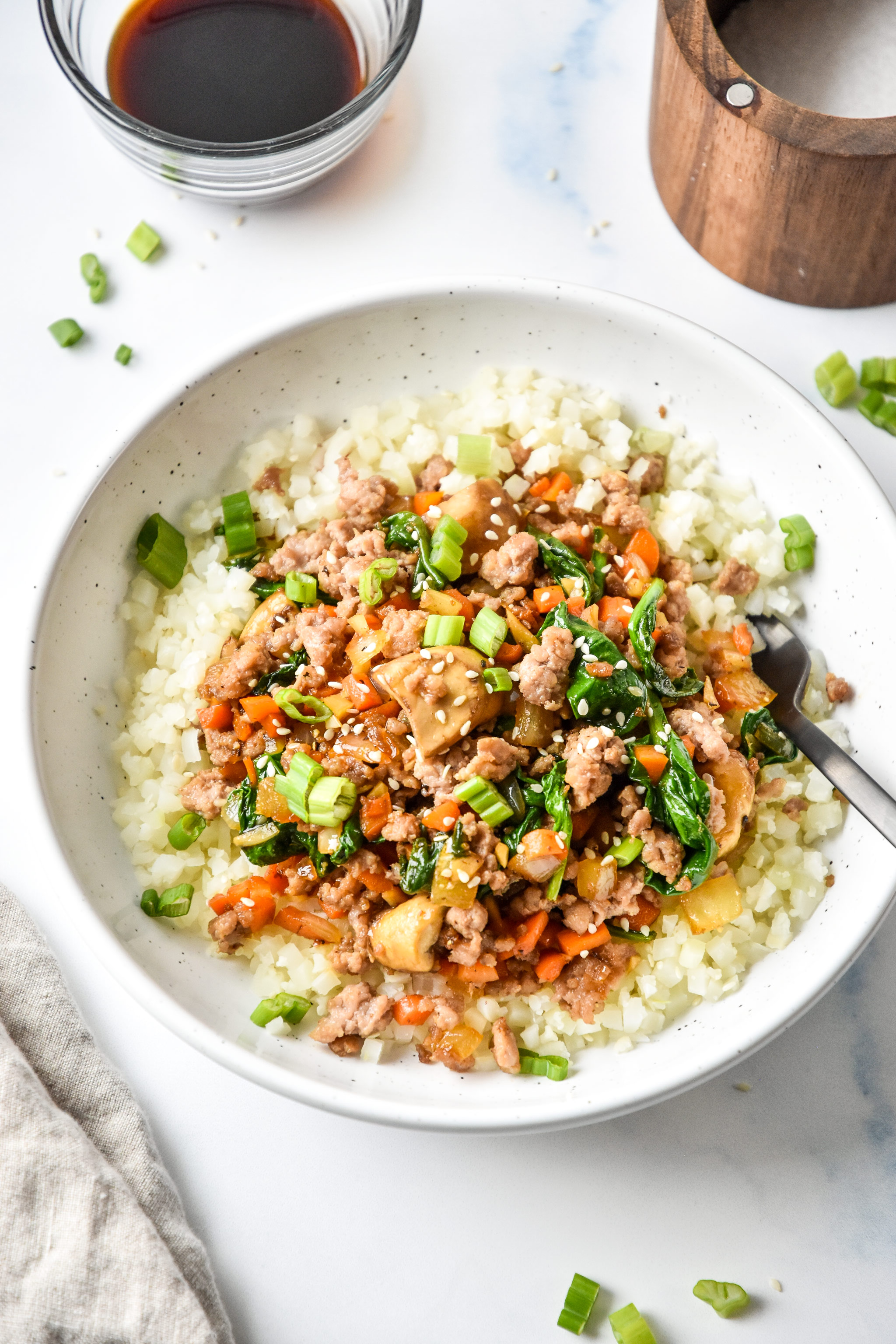 one serving vegetable pork bowl served with cauliflower rice and green onions on top