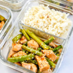 meal prep spicy chicken asparagus meal with rice in a glass meal prep container
