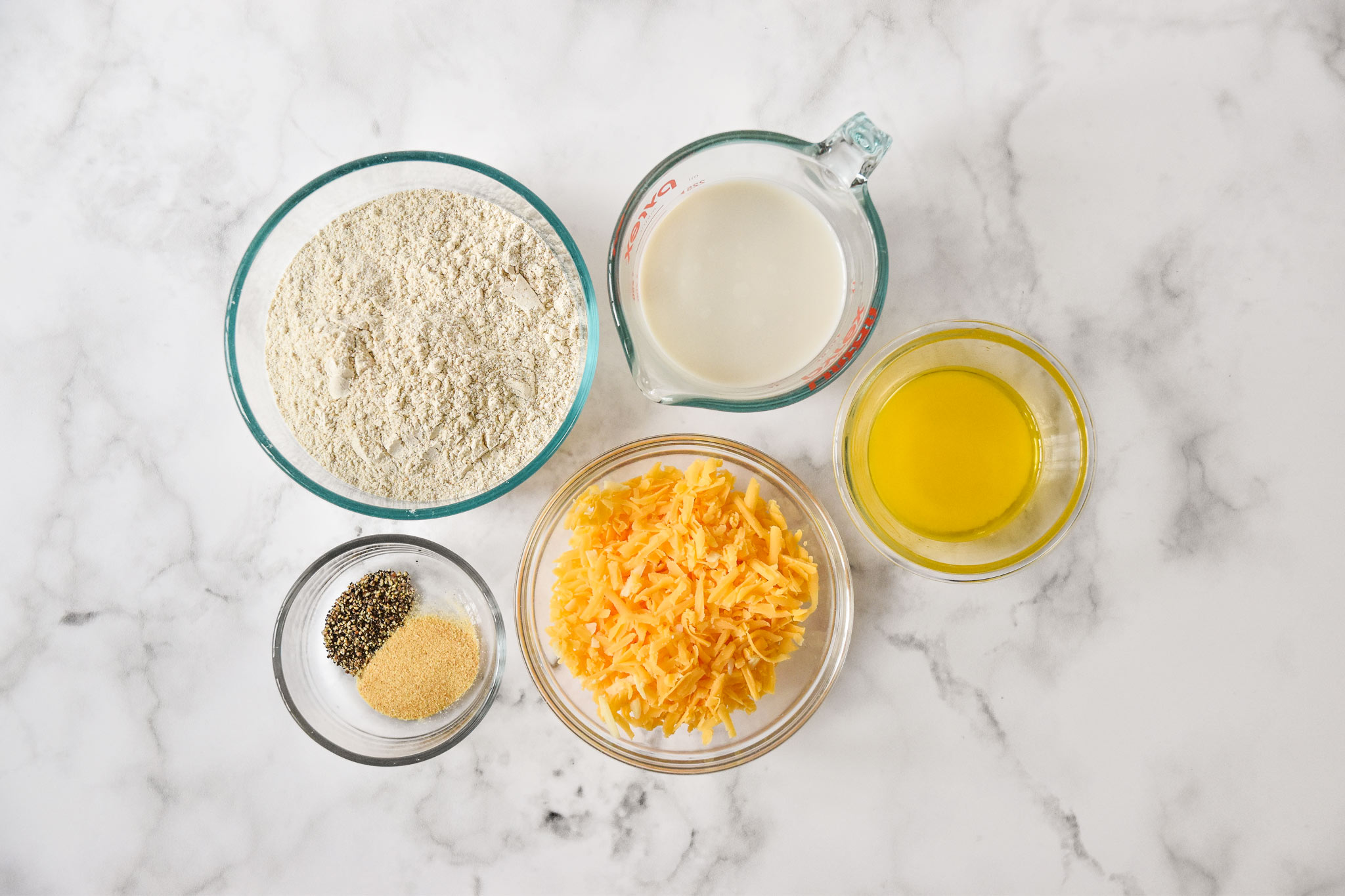 ingredients in separate bowls for the pancake mix cheddar drop biscuits.
