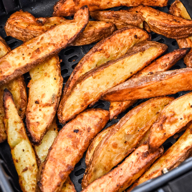 close up of cooked jojo potato wedges in an air fryer basket.