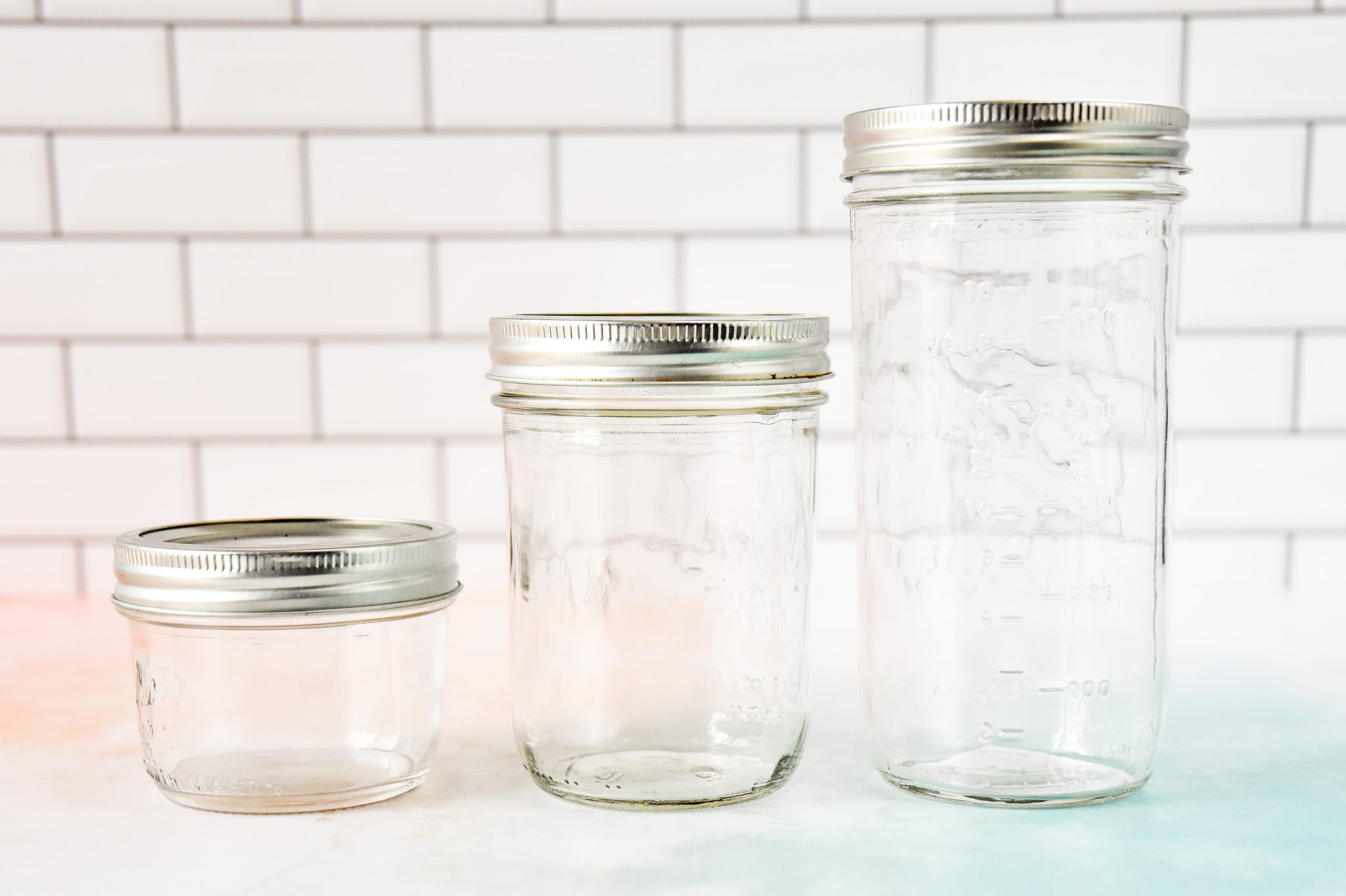 wide mouth mason jars in three sizes on a counter.
