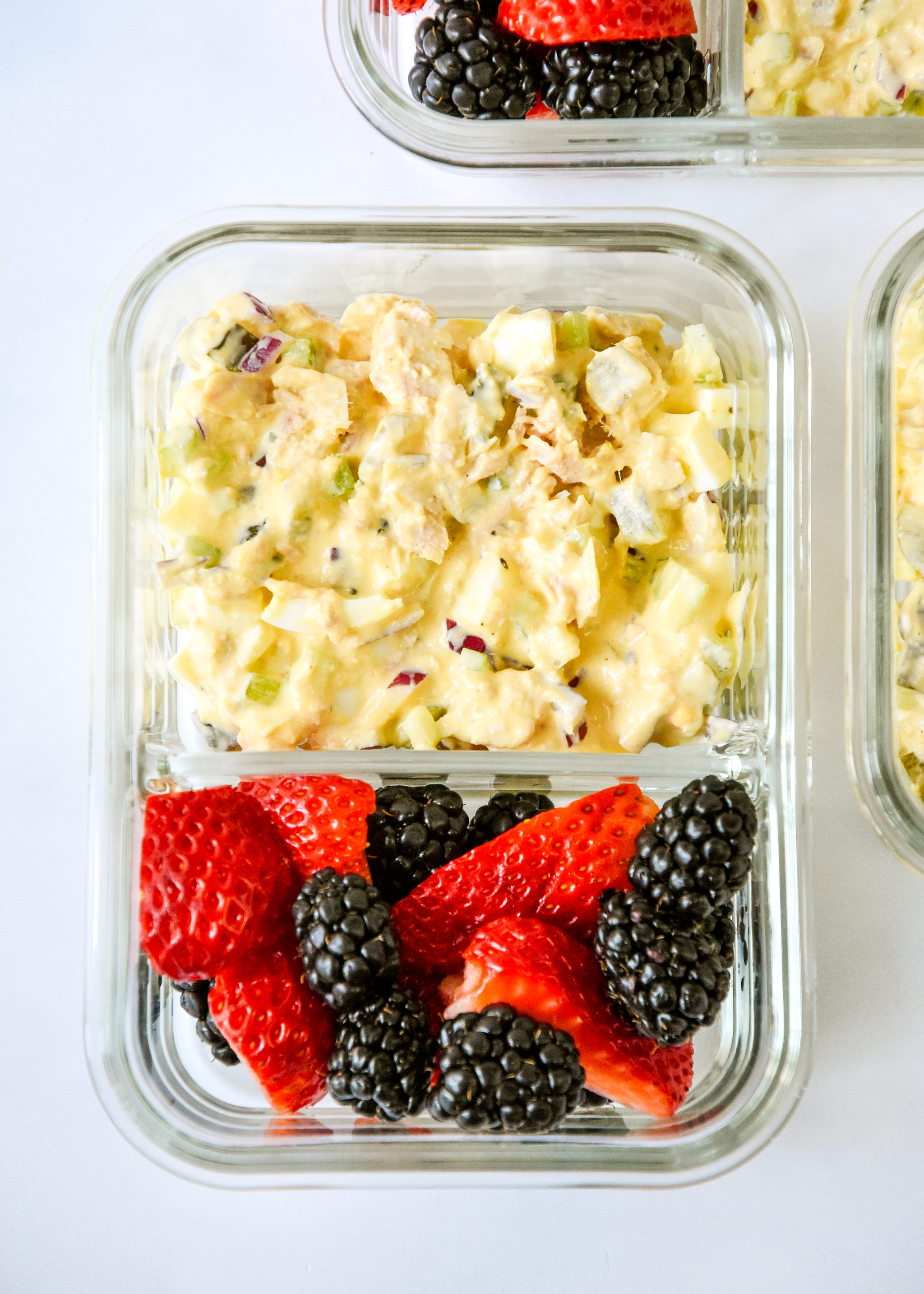 tuna egg salad in a meal prep container with fresh berries.