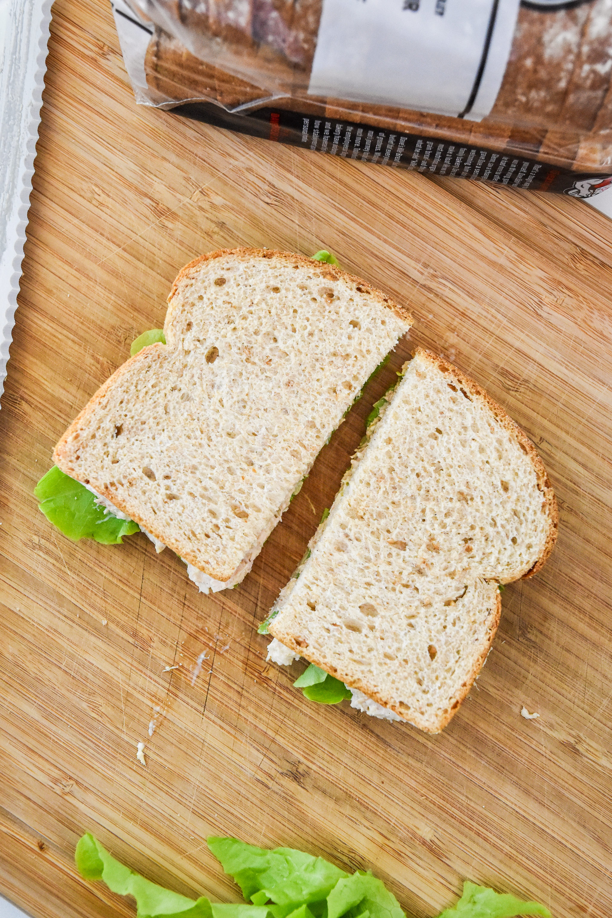 tuna sandwich made with lazy no chop tuna salad cut in half on a cutting board.