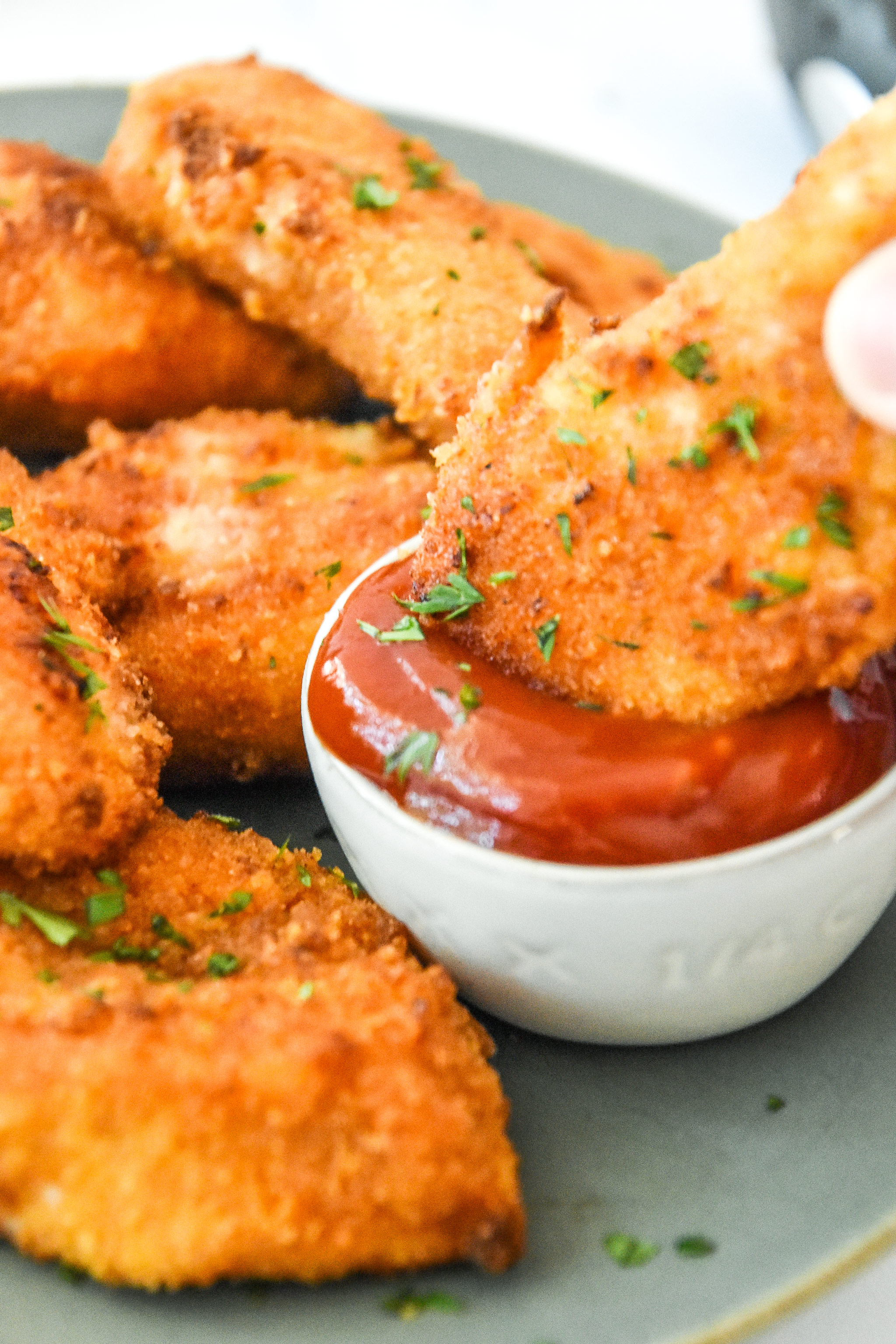 dipping a breaded chicken tender into ketchup.