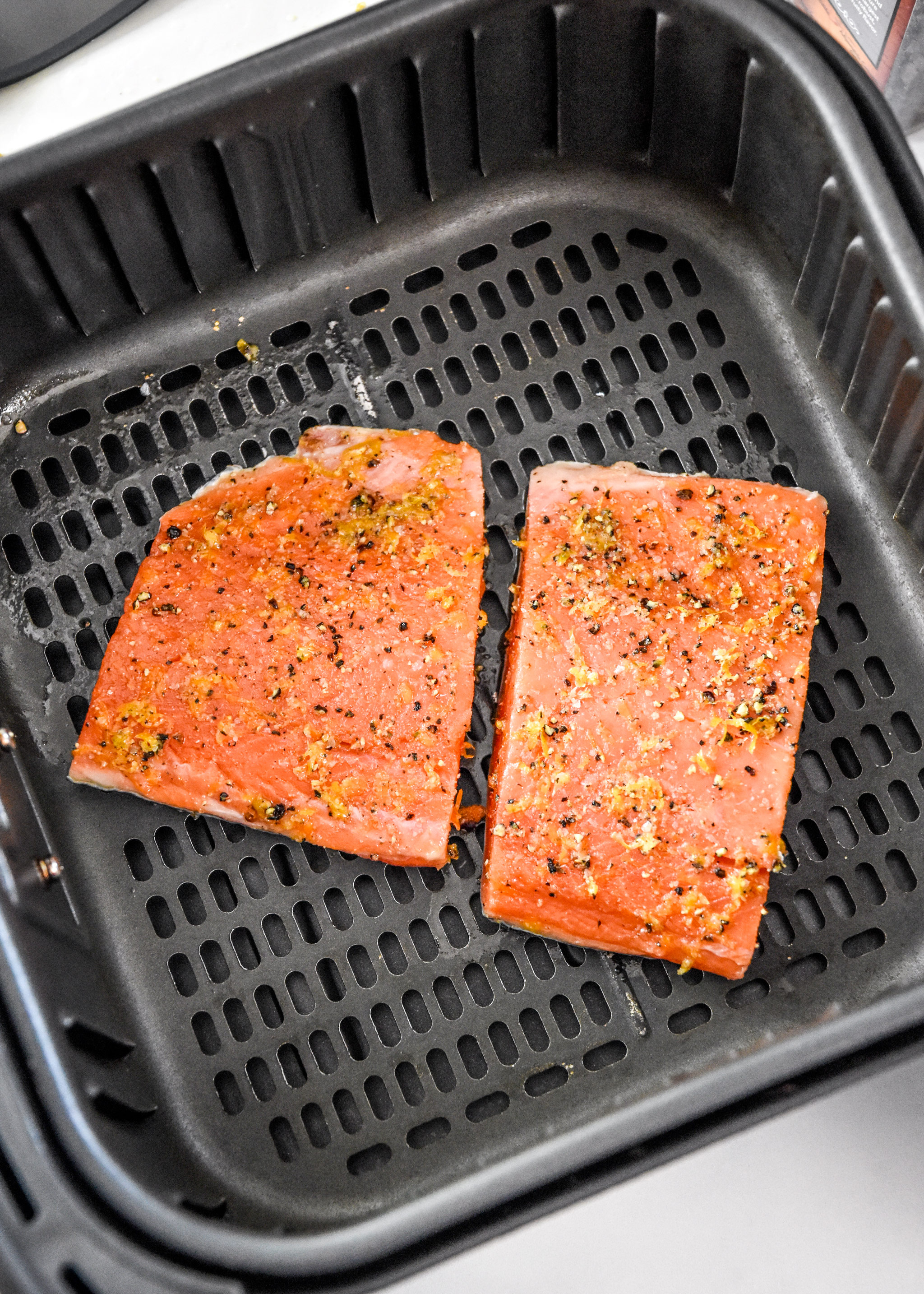 raw salmon in the air fryer basket about to be cooked.