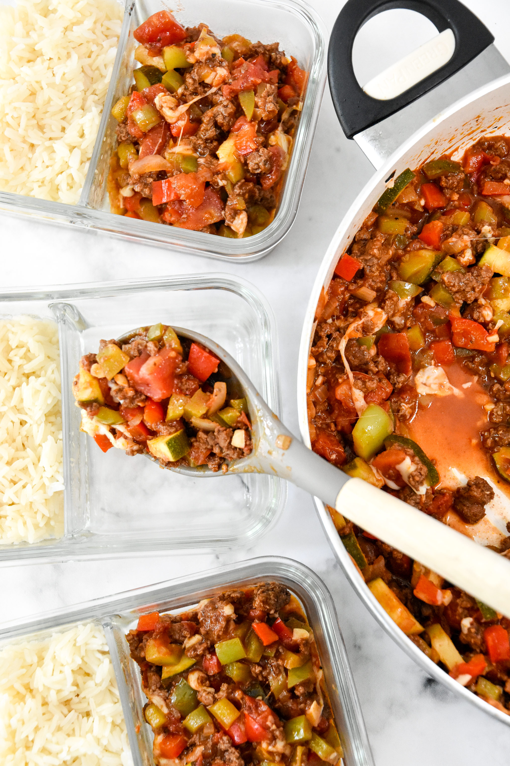 spooning unstuffed pepper mixture into the glass meal prep containers.