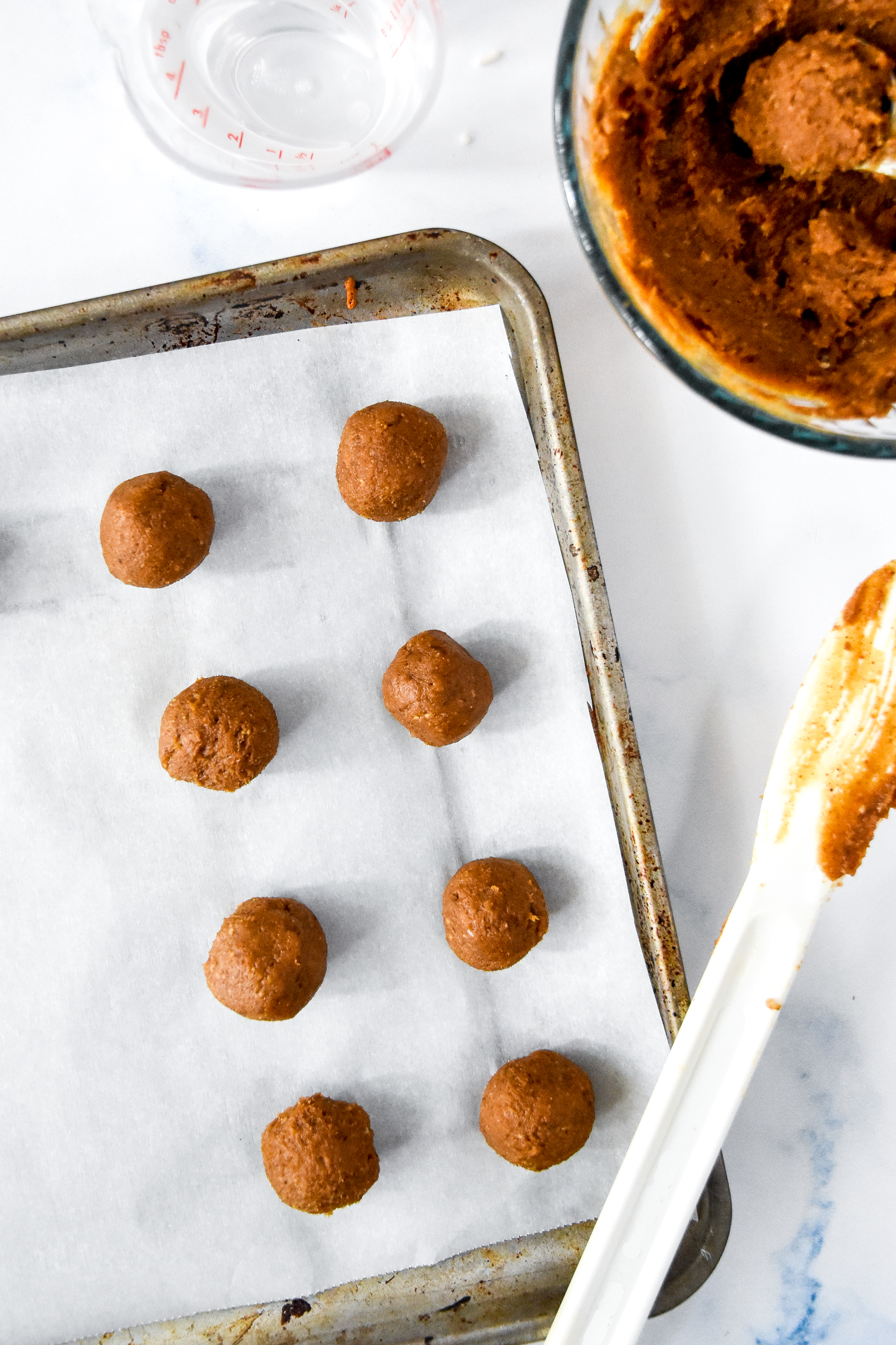 rolling date balls and placing on a parchment paper lined cookie sheet.