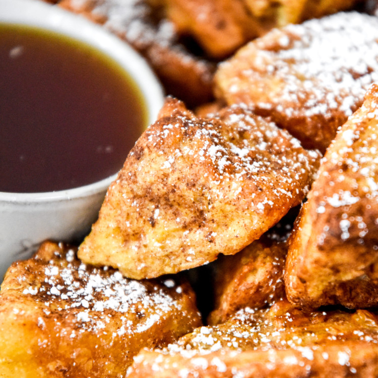 close up of air fryer french toast bites on a plate with powdered sugar.