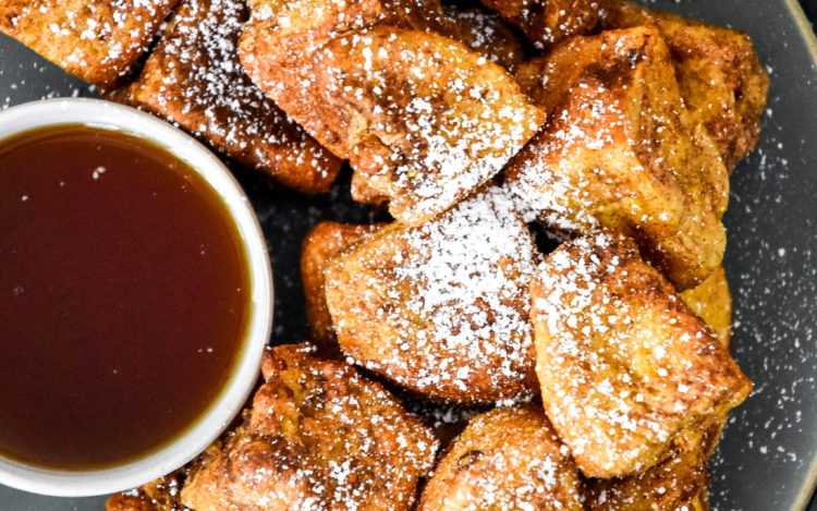 air fryer french toast bites on a plate with cup of syrup.
