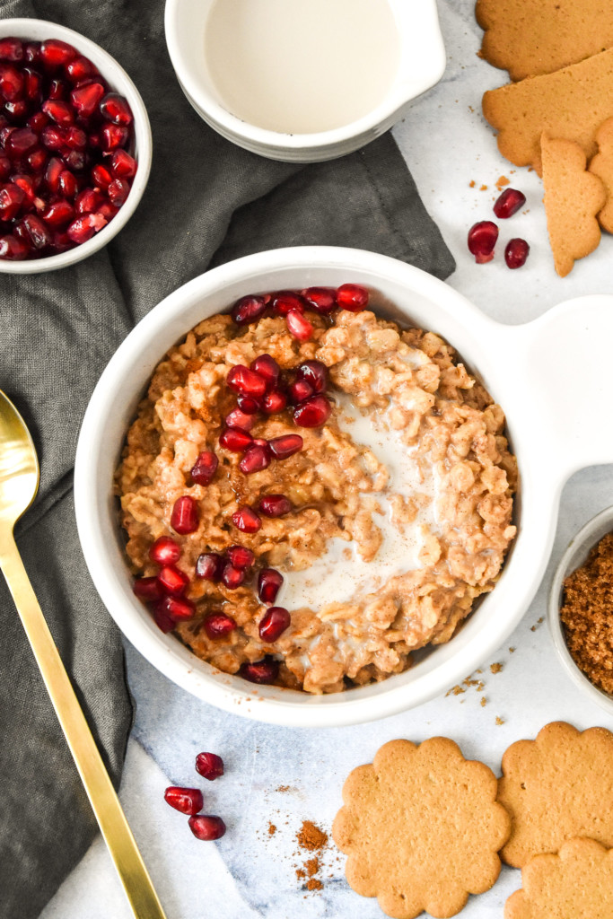 a bowl of instant pot gingerbread oatmeal with milk and pomegranate seeds topping.