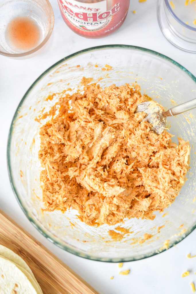 ingredients for the air fryer buffalo chicken flautas mixed up in a glass bowl.