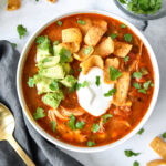 bowl of instant pot no bean chicken chili with sour cream, avocado and corn chips on top.