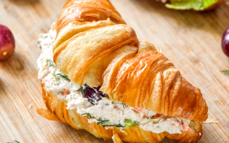 easy chicken salad with grapes on a croissant on a cutting board.