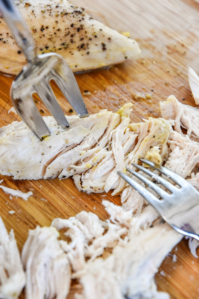 shredding chicken on a cutting board.