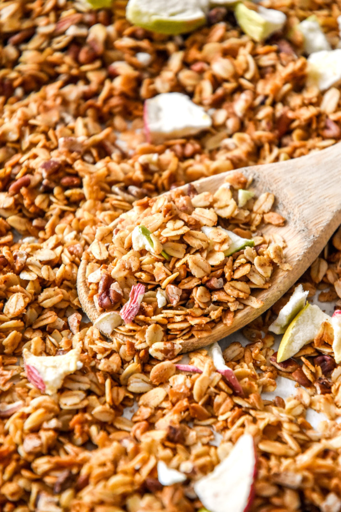 homemade apple pie spiced granola fresh baked on a sheet pan with wooden spoon.