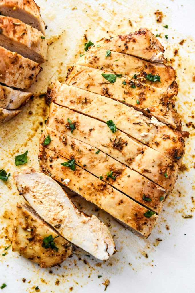 juicy air fryer chicken breasts cut into slices on a cutting board.