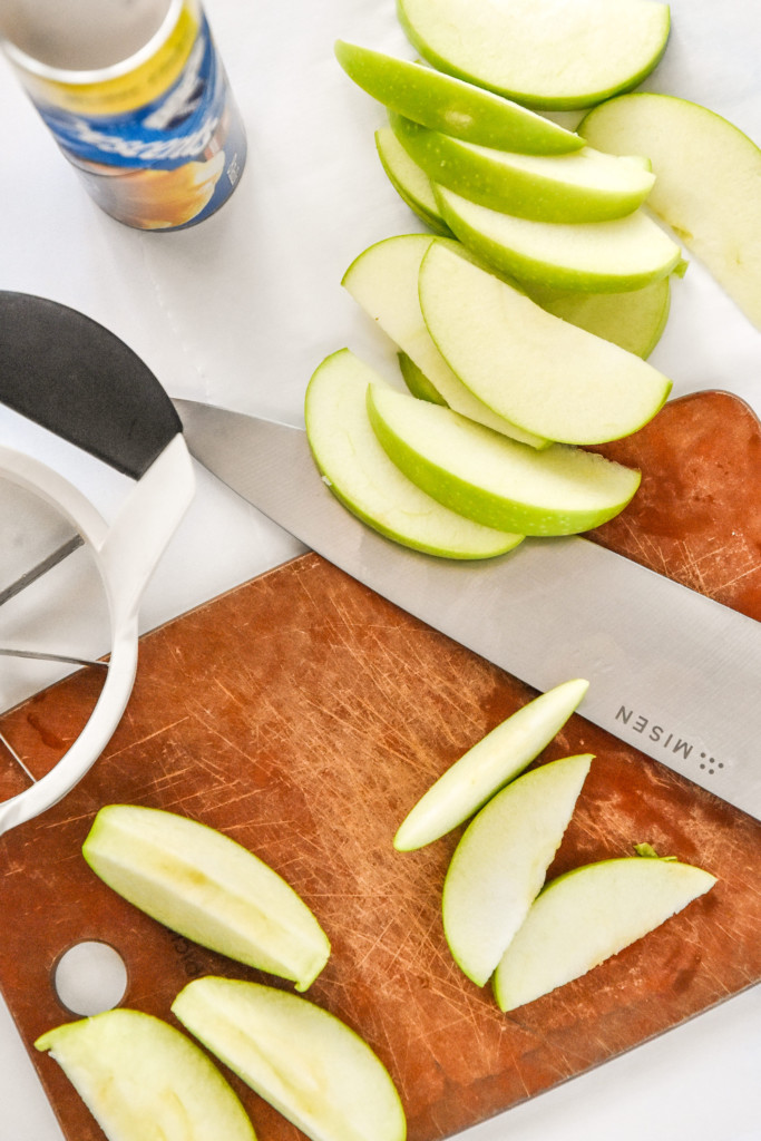 cutting up apples on a cutting board to make air fryer apple pie crescent rolls.