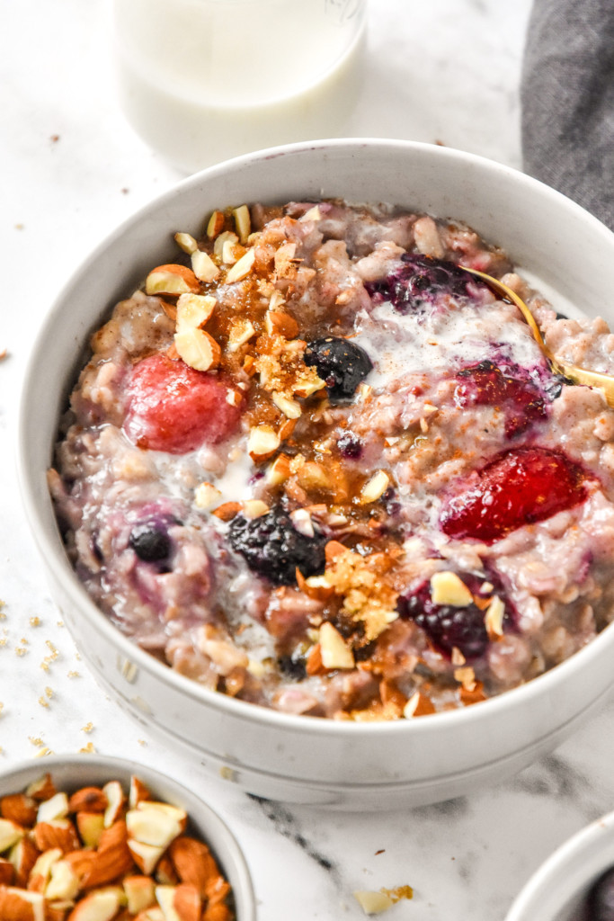 bowl of stovetop triple berry egg white oatmeal in a bowl with almonds on top.
