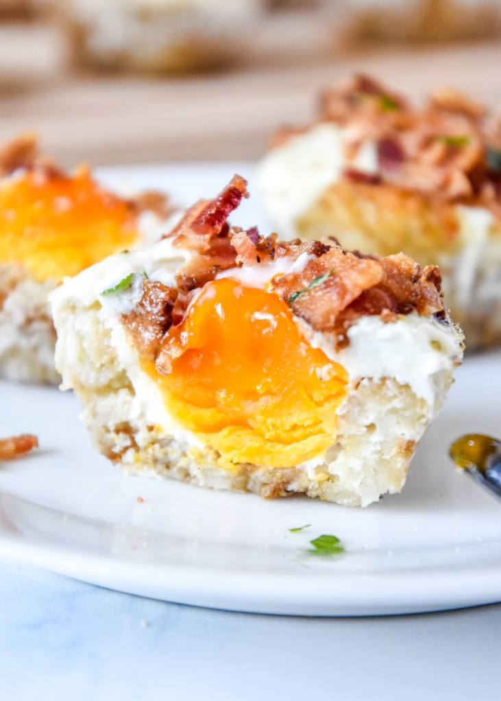 Tater Tot Crust Baked Egg Muffins on a plate cut in half showing the yolk inside.
