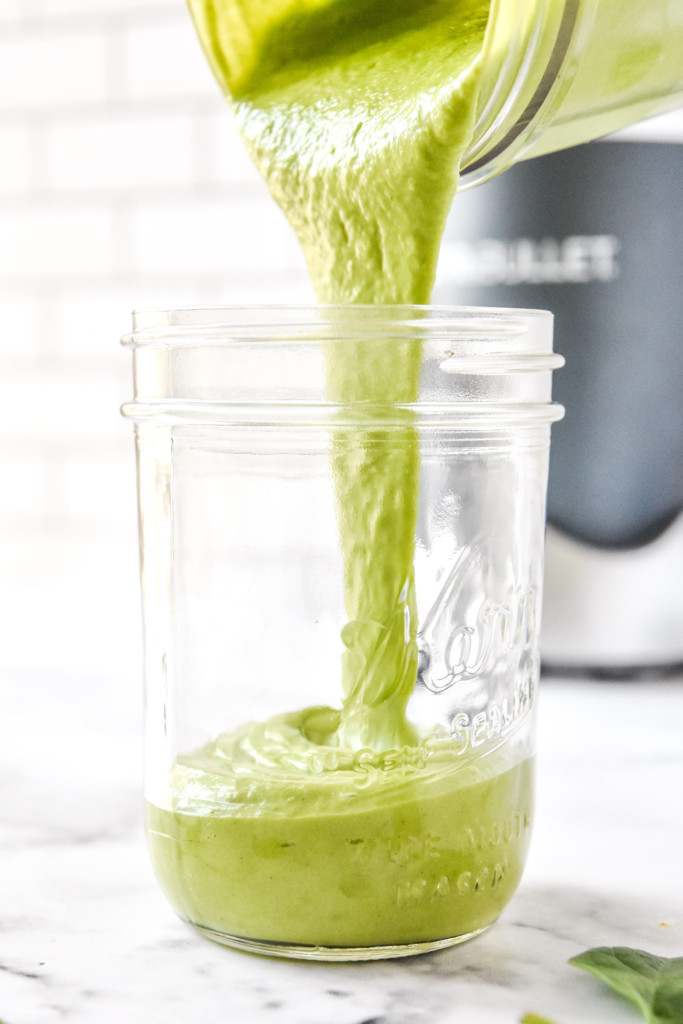 pouring the green smoothie into a mason jar for serving.