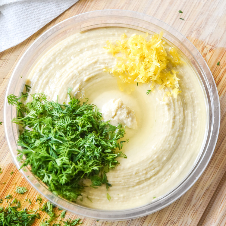 making lemon dill hummus for the with fresh lemon zest and chopped dill.