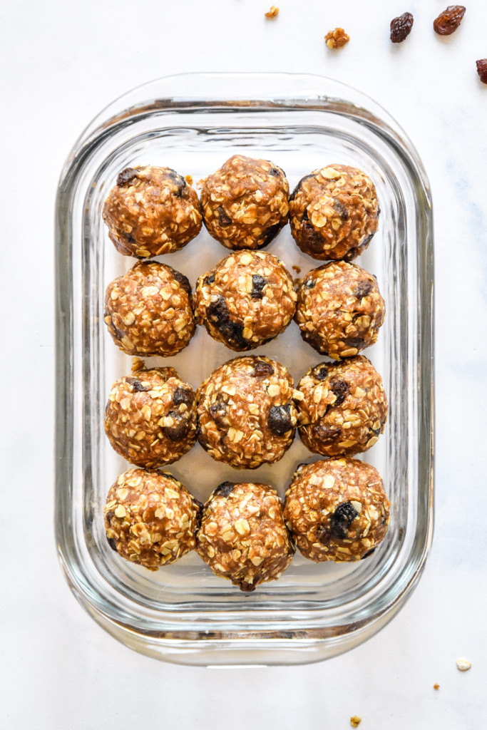 no-bake oatmeal raisin cookie balls rolled up and stored in a glass meal prep container.