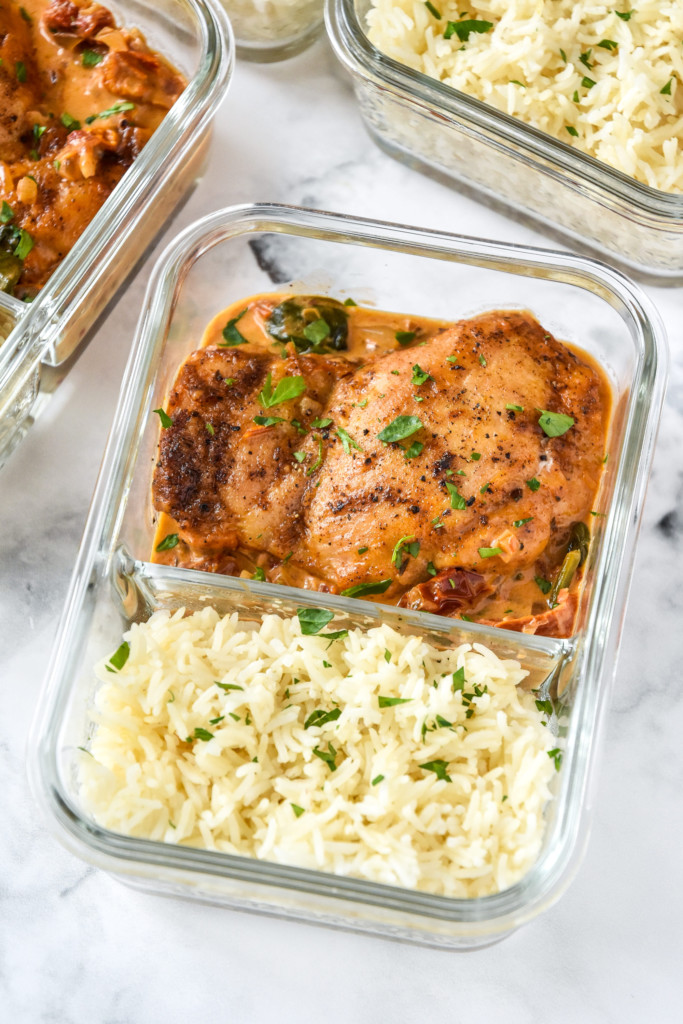 creamy tuscan chicken meal prep with rice in a glass meal prep container.