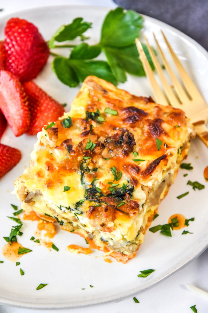a serving on spinach feta chicken sausage breakfast casserole on a plate with strawberries.