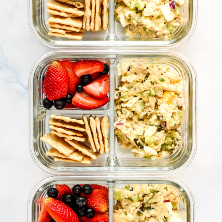 tuna egg salad meal prep with berries and crackers in glass meal prep containers.