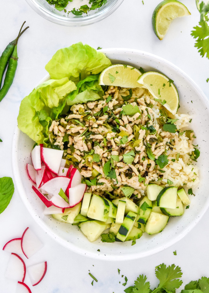thai chicken larb inspired meal prep recipe plated with fresh veggies and limes.