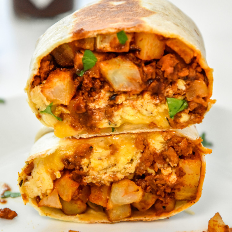 meal prep soy chorizo breakfast burritos cut in half and stacked on a plate.