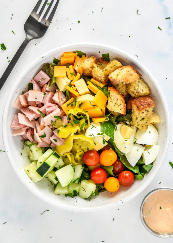 plated chef salad with fresh veggies, croutons, meat and cheese on a bed of romaine.