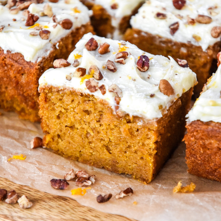 a slice of sweet potato spice cake with cream cheese frosting and chopped pecans on top.