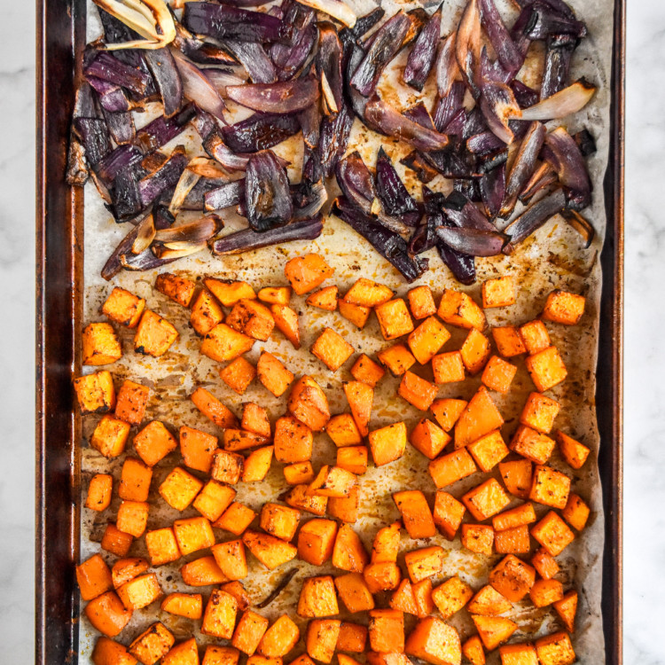 cooked butternut squash and red onions on a sheet pan for the roasted butternut squash couscous salad.