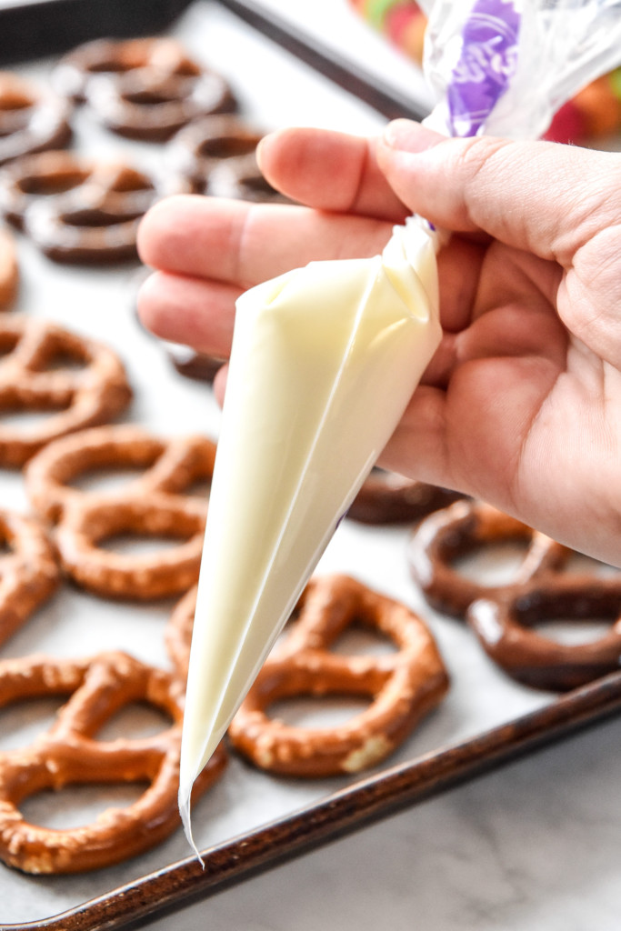 white chocolate in a piping bag with pretzels in the background.