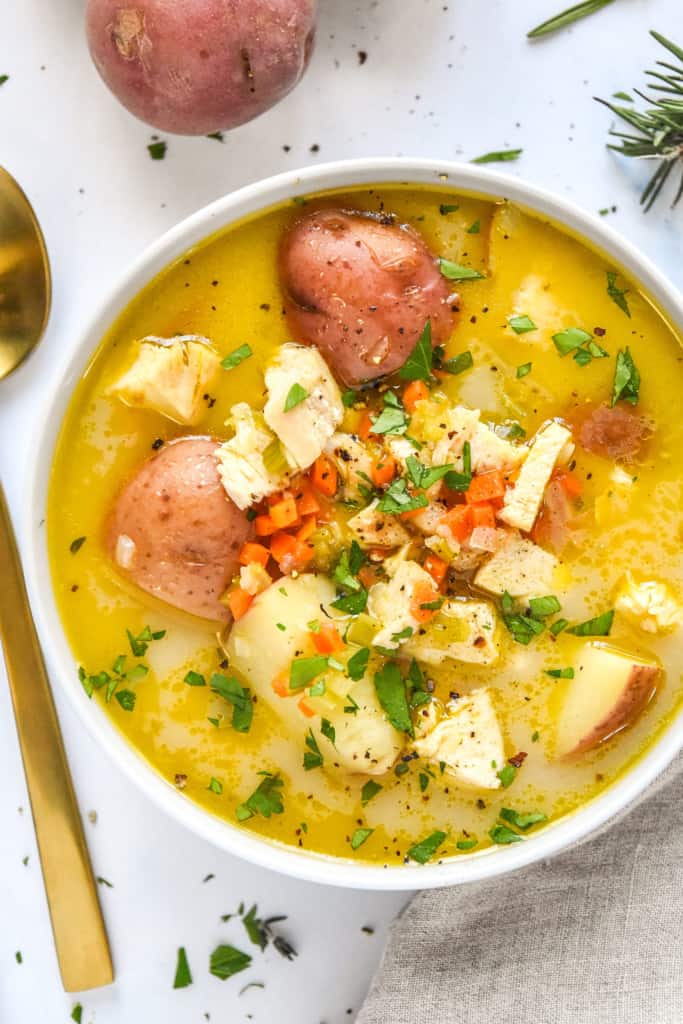 simple red potato chicken soup in a bowl on a white table.