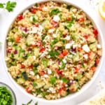 make-ahead quinoa party salad in a large serving bowl with feta and parsley on top.