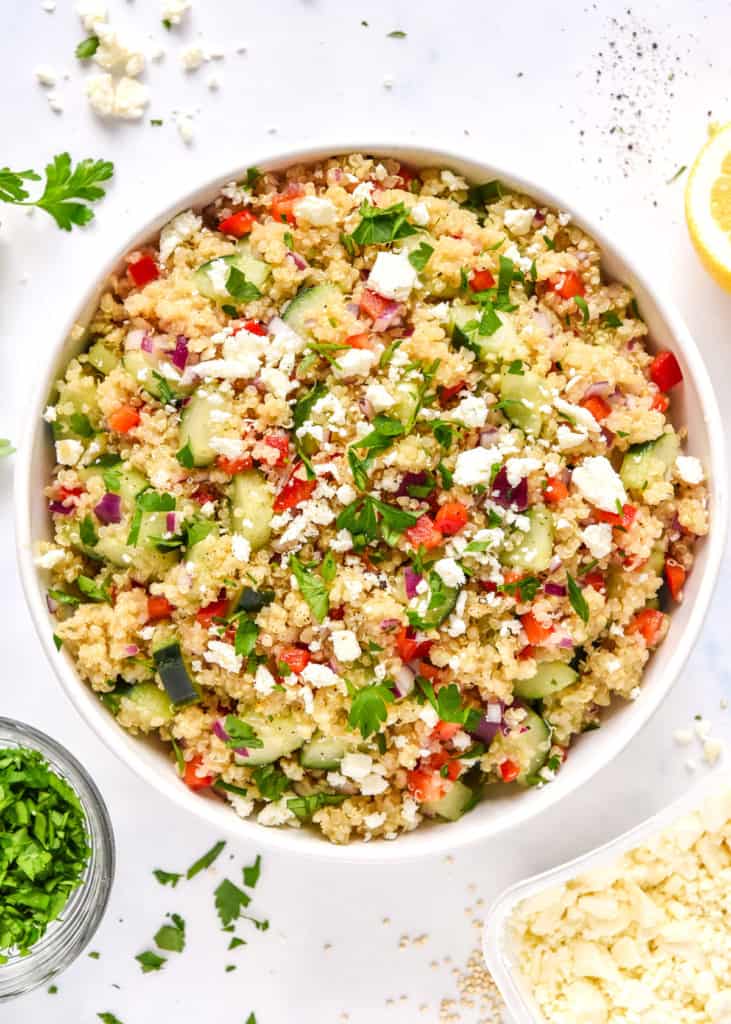 make-ahead quinoa party salad in a large serving bowl with feta and parsley on top.