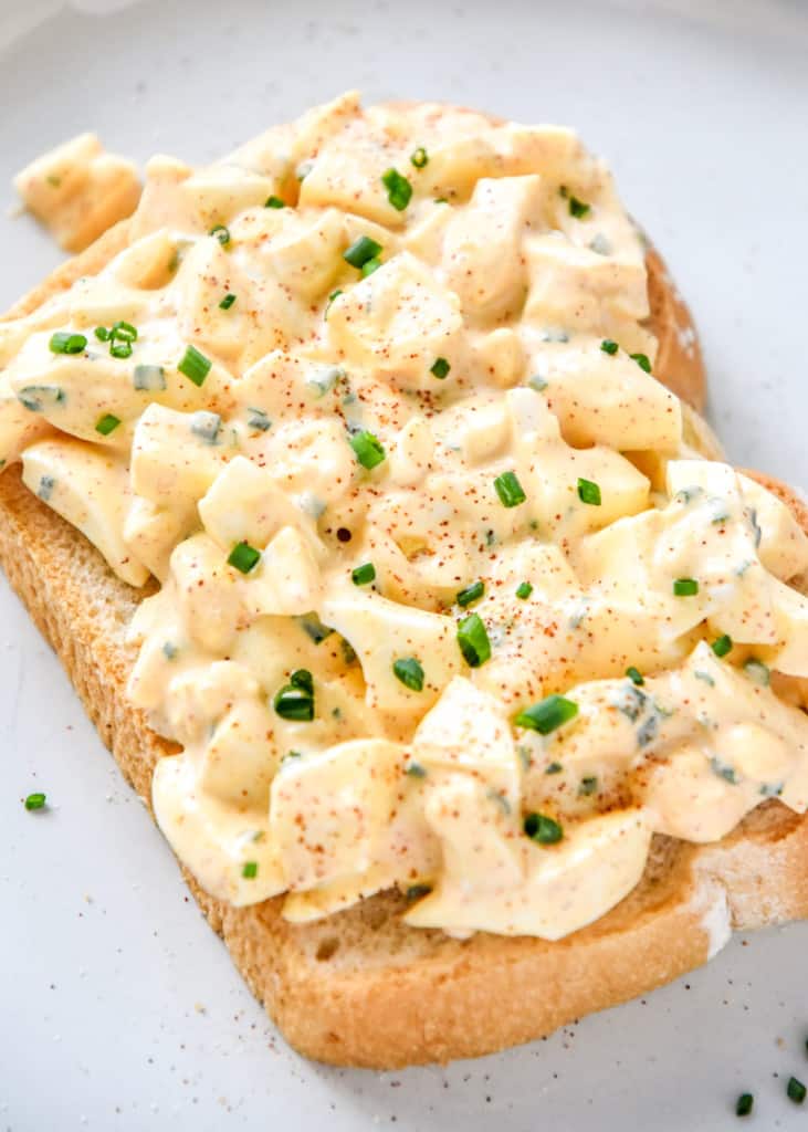 easy deviled egg salad on a piece of bread with fresh chives and paprika.